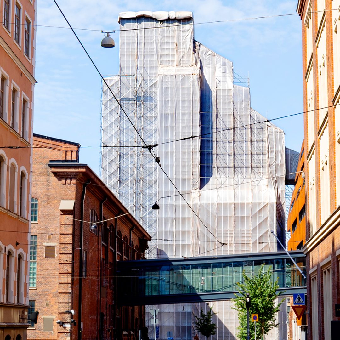 Telineisiin ja sääsuojaan verhottu Hietalahden nosturi näkyy Helsingin katunäkymän päätteenä