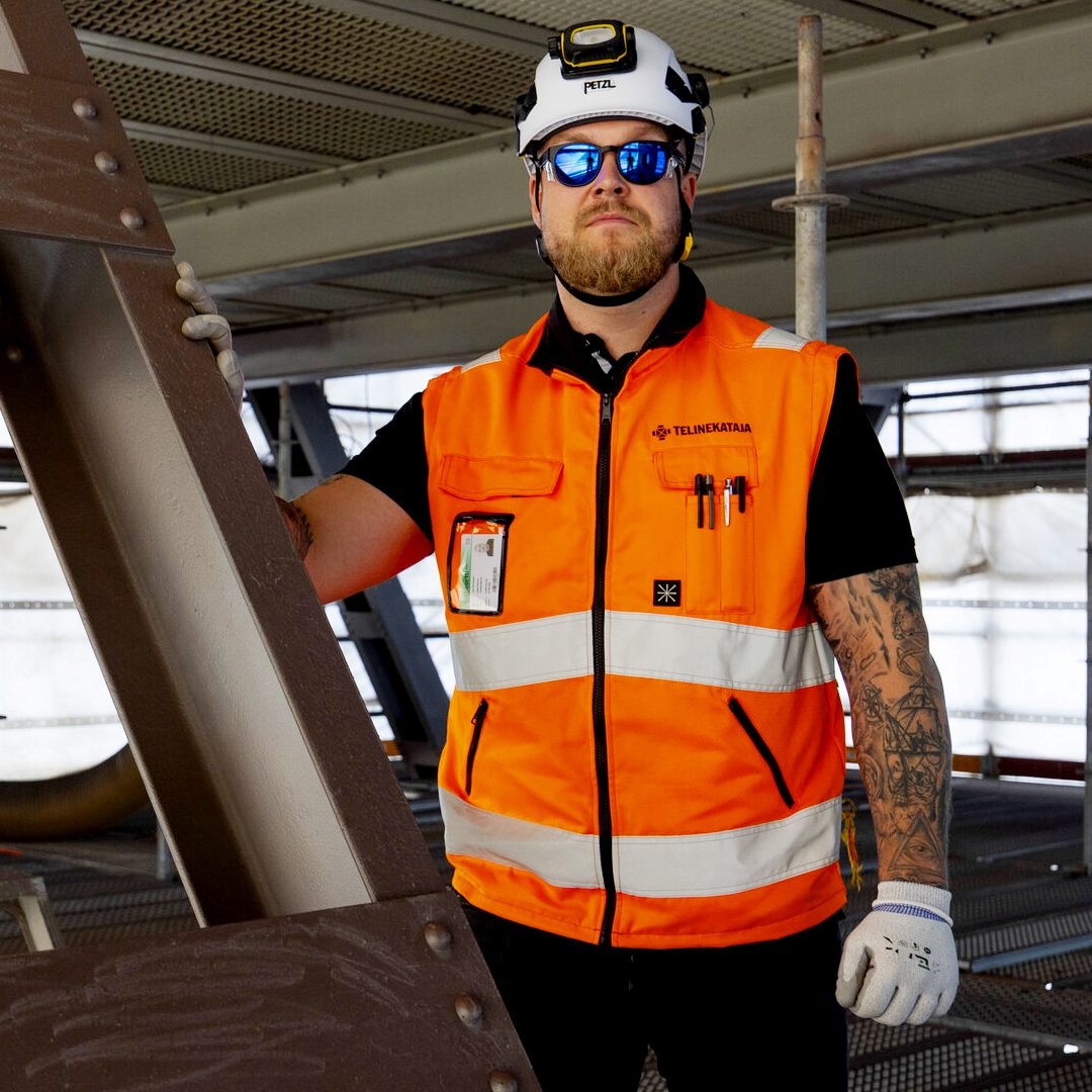 Telinekatajan telineasentaja oranssissa huomioliivissä ja kypärässä Hietalahden nosturin työtasolla